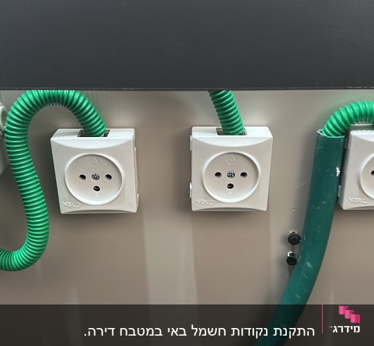 שלושה שקעים עם כבלים ירוקים על קיר